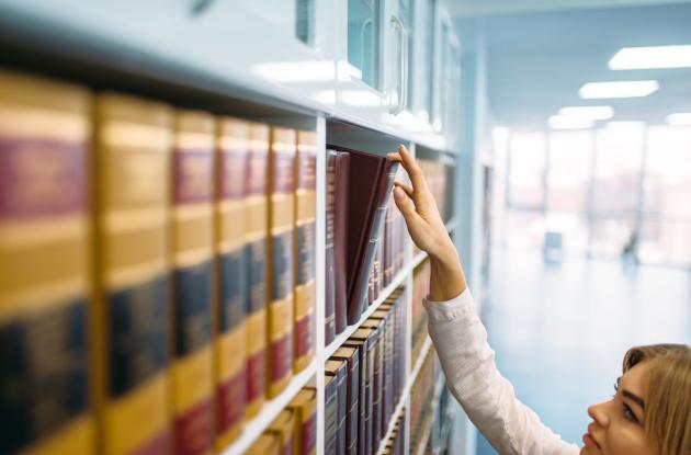 Librarian reaches for book on bookshelf